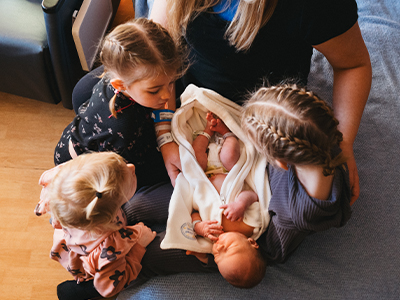 jrmc-family-birthplace-sisters-meeting-new-sibling Image of sisters meeting new baby sibling