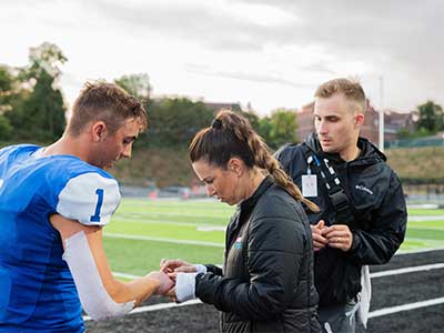 Orthopedic Nurse Practitioner Crystal Krapp reviews an injury at a Jamestown High School football game.