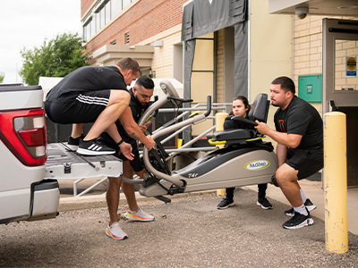 Image of University of Jamestown loading NuStep machine from JRMC.