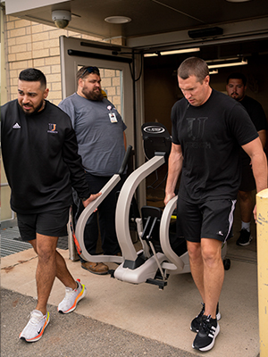 Image of University of Jamestown personnel moving the NuStep machine.