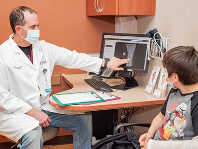 image of Dr. Timothy Volk visiting with young patient